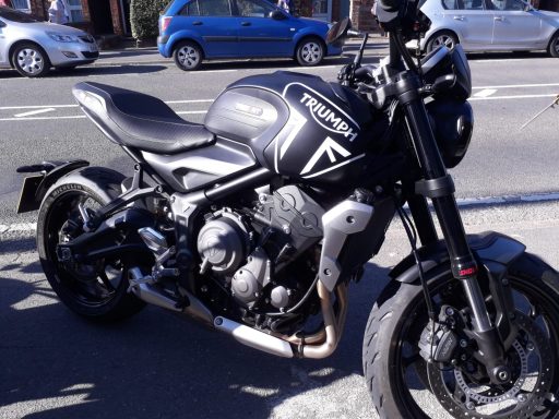 Black motorcycle parked on the street, featuring a sporty design and side exhaust.