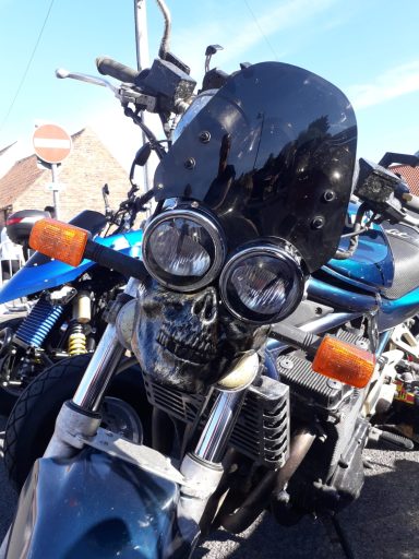 Close-up of a motorcycle with a custom black windscreen and dual headlights.