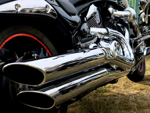 Close-up of a motorcycle exhaust with shiny chrome pipes and red rim accents.