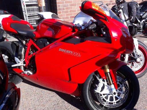 Red Ducati motorcycle parked among other bikes.