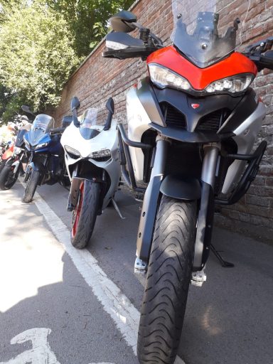 Two motorcycles parked side by side on a street, one with a red and black design.