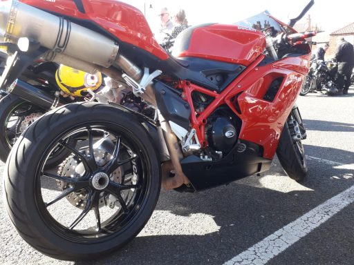 Red sports motorcycle parked on a paved surface, featuring a sleek design and visible exhaust.