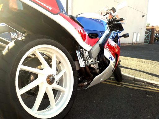 Sport motorcycle with a distinctive red, blue, and white design parked on the street.