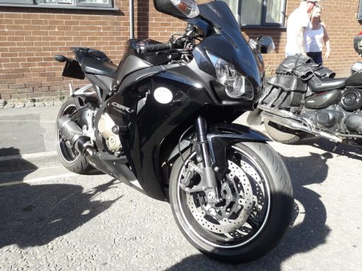 Sleek black sports motorcycle parked on a gravel surface.