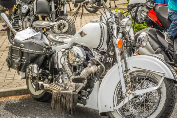 White vintage motorcycle with chrome details parked among other bikes.