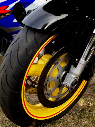 Close-up of a motorcycle wheel with a black tyre and yellow accent on the rim.